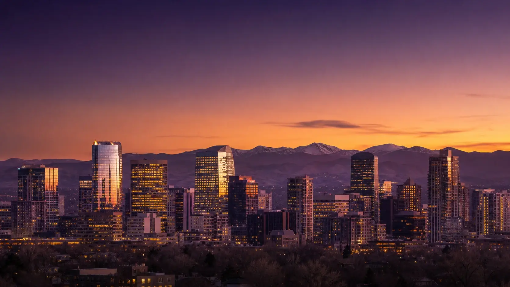 The Denver skyline at sunset against the Rocky Mountains, home of Inclusive Law Group
